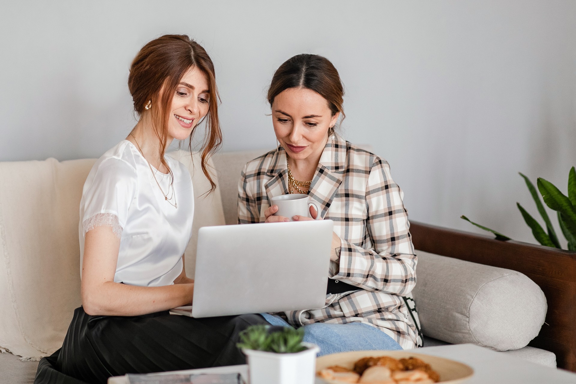 One-on-one meeting.Two young business women sit at a Desk in the office. The girl shows her colleague information on the laptop screen. Women discuss their work online and blog.