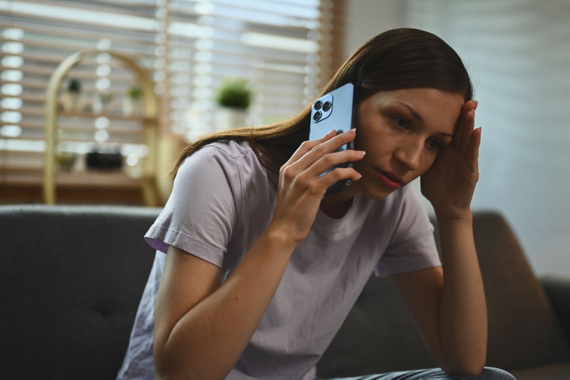 Concerned young woman having unpleasant phone conversation receiving bad news and feeling desperate