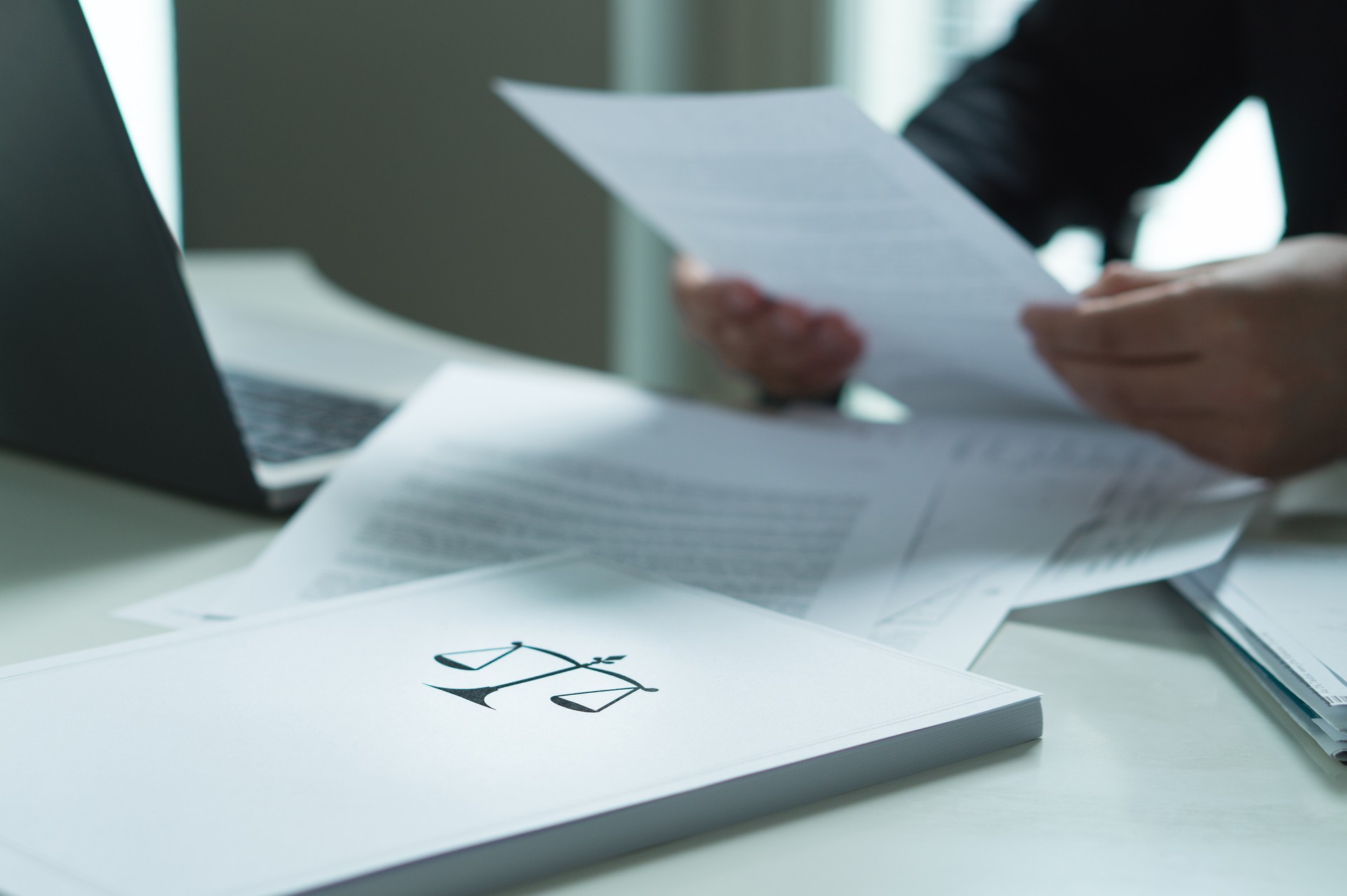 Man holding a legal document in hand. Lawyer holding law paper in office. Scale and justice symbol.